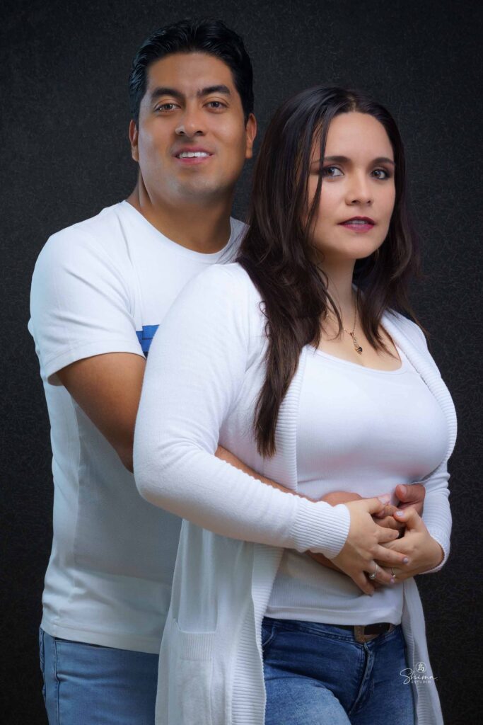 Pareja abrazada de frente a la cámara sobre fondo oscuro, sesión de pareja en Barranco