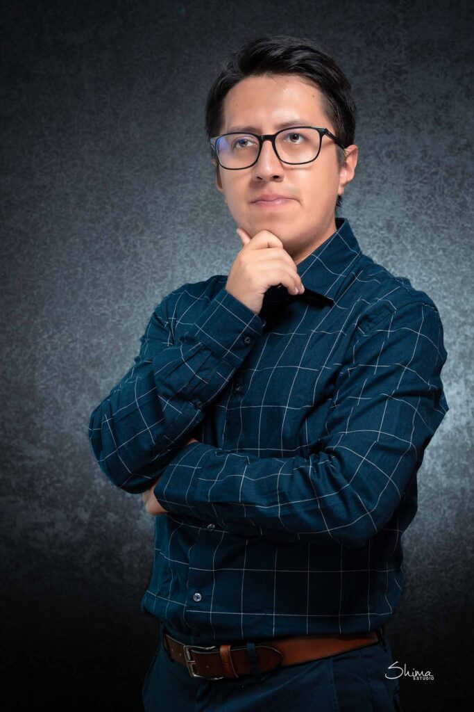 Foto corporativa de hombre con camisa azul y mano en la barbilla, estudio en Lima