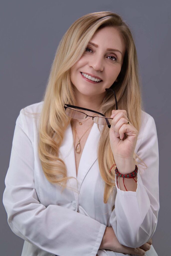 Foto de perfil profesional de mujer con blazer blanco sosteniendo sus gafas, estudio en Barranco, Lima