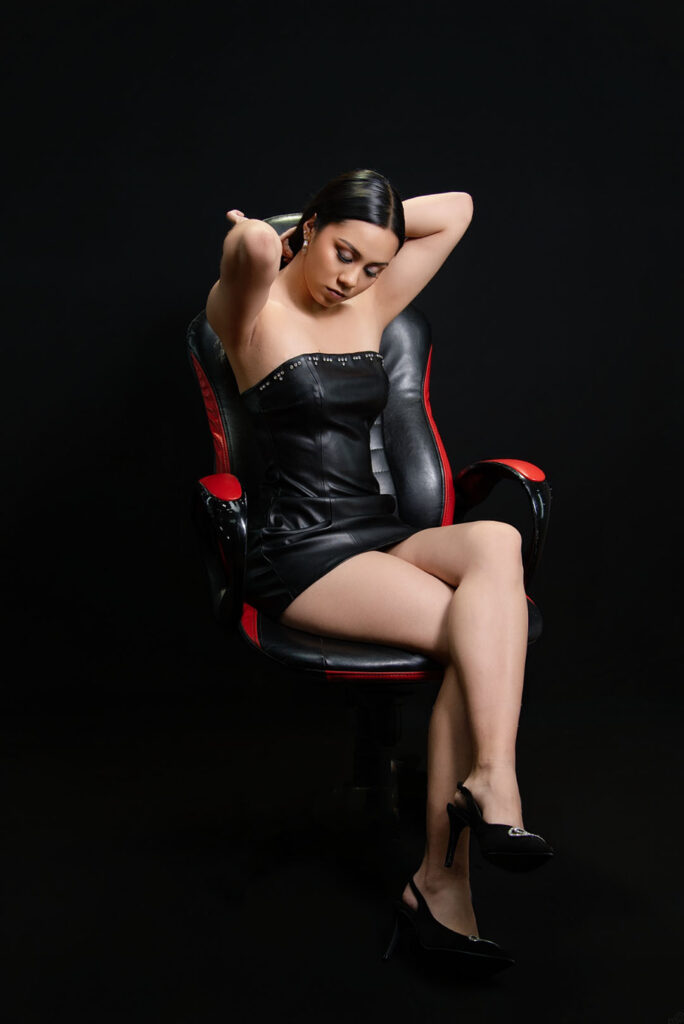 Retrato creativo en sillón rojo con el brazo sobre la cabeza, estudio fotográfico en Lima