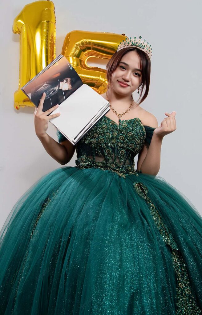 Quinceañera con vestido verde junto a globos dorados con el número 15, sesión de 15 años en Barranco